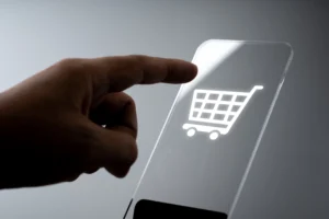 Pessoa realizando compra online em celular com símbolo de e-commerce na tela.